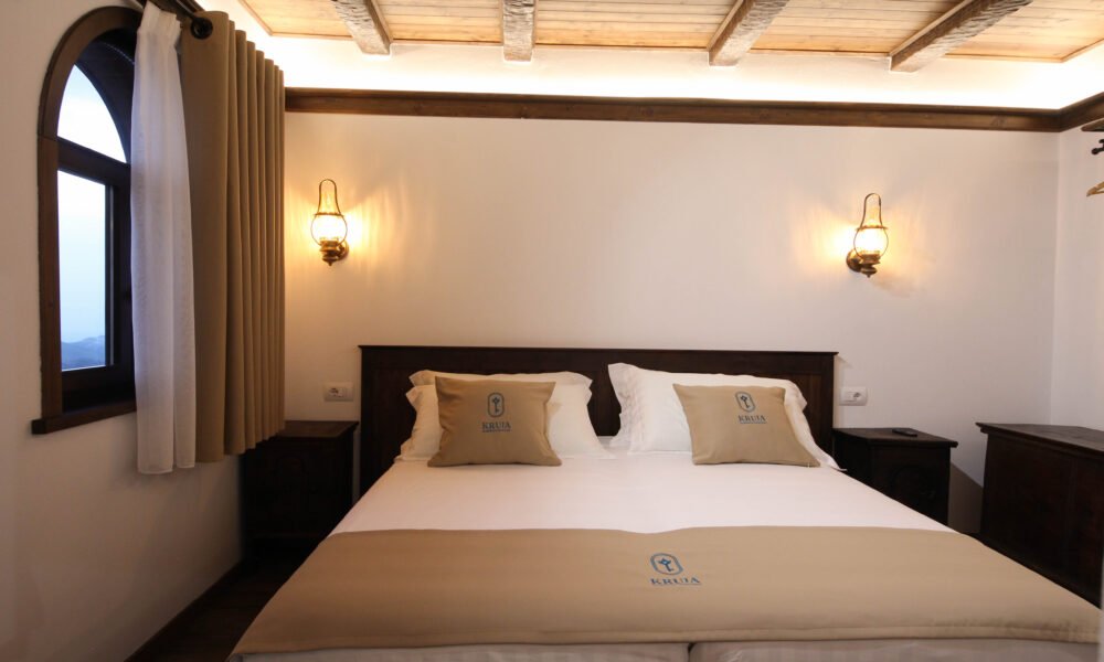 Bed beside the arched window of the Deluxe Double Room with Sea View at Kruja Albergo Diffuso