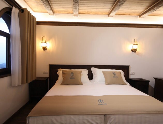 Bed beside the arched window of the Deluxe Double Room with Sea View at Kruja Albergo Diffuso